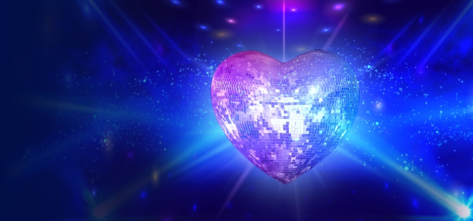 A silver heart-shaped disco ball shines against a sparkling dark blue background