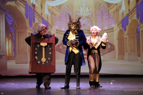 A trio of performers in front of a castle interior digital projection