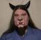 A man wearing a foam latex beast face prosthetic with makeup, beard and horns.